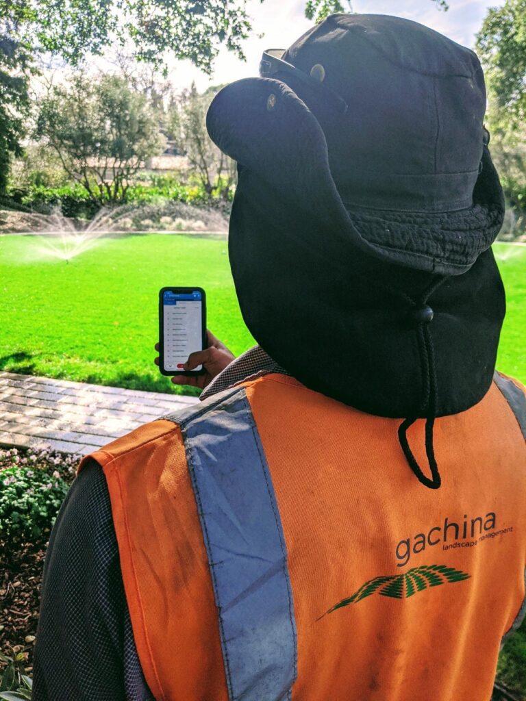 employee taking a photo of a newly installed water sprinkler on a lawn